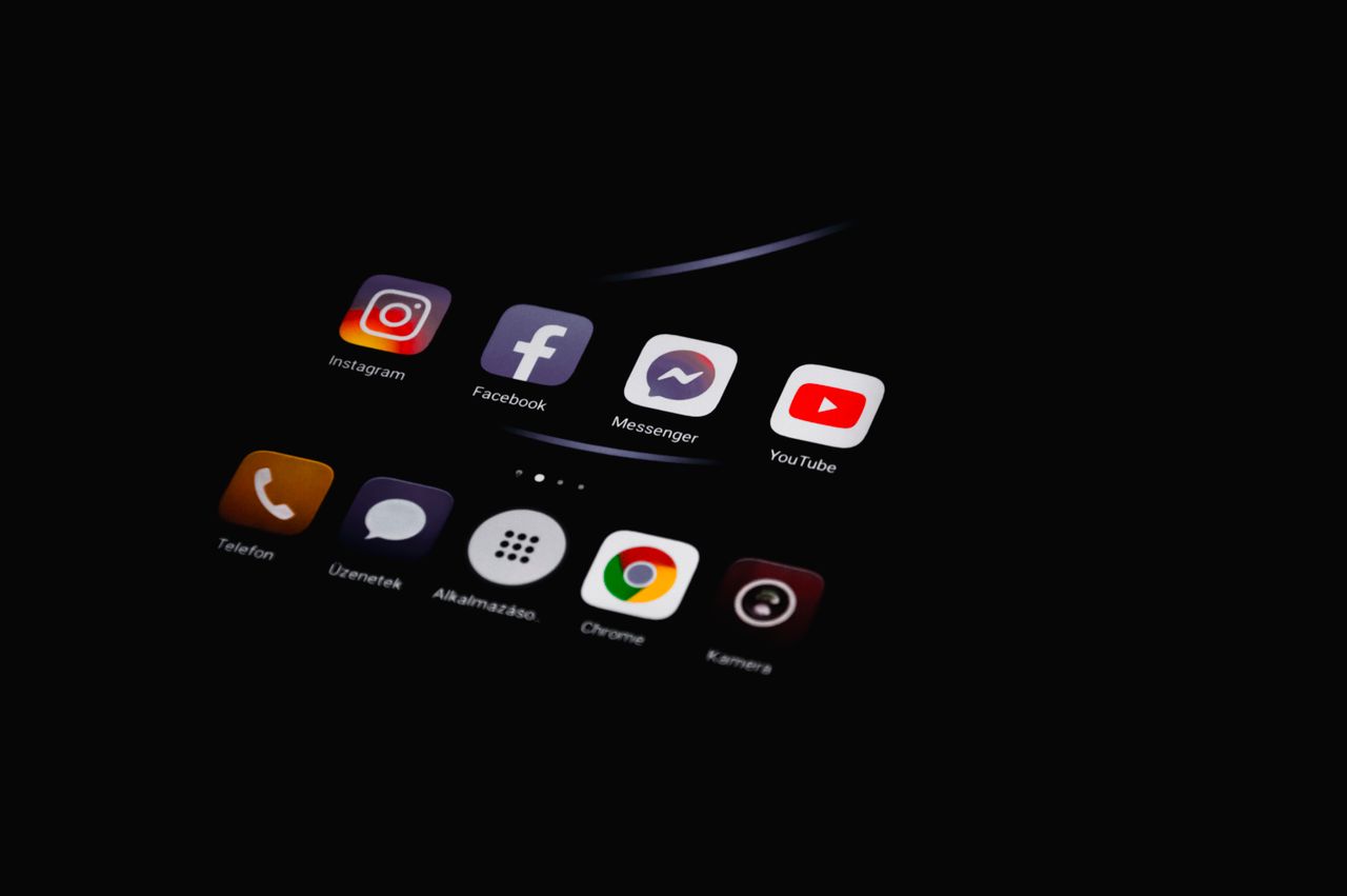 Close-up of smartphone displaying popular social media apps in dim lighting.